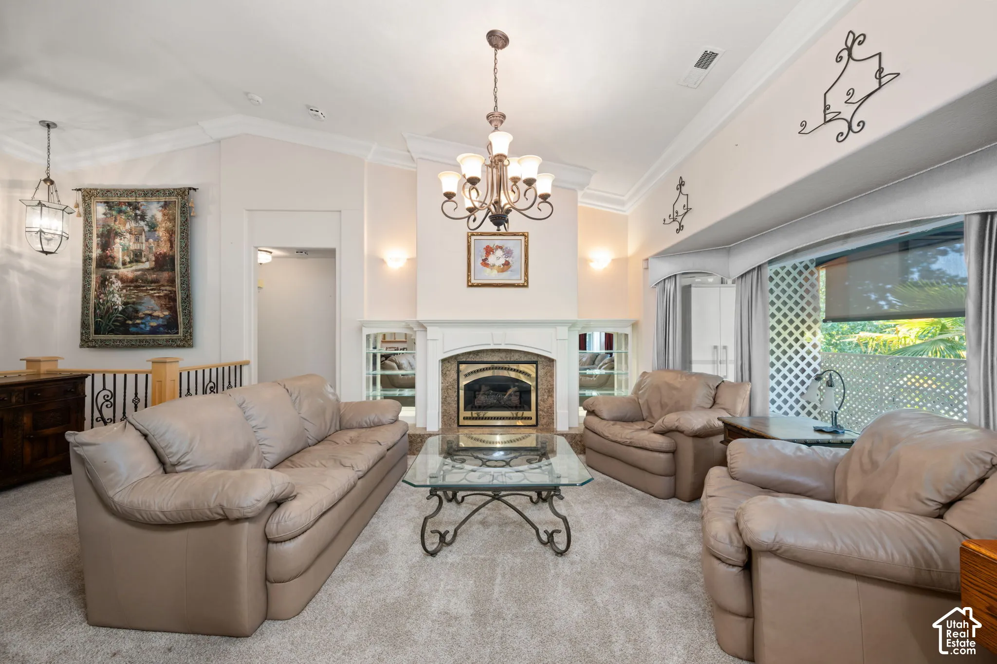 Living area featuring a fireplace with a decorative mantel, built-in shelving, vaulted ceilings with crown molding, and a bay window