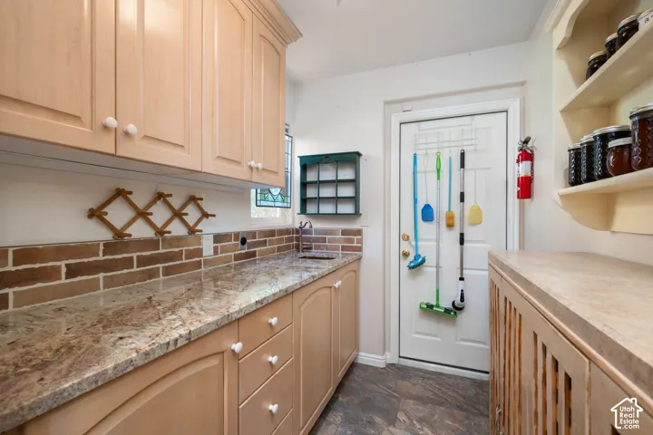Light wood-finish cabinetry with white knobs, granite-style countertops, and a brick-patterned backsplash