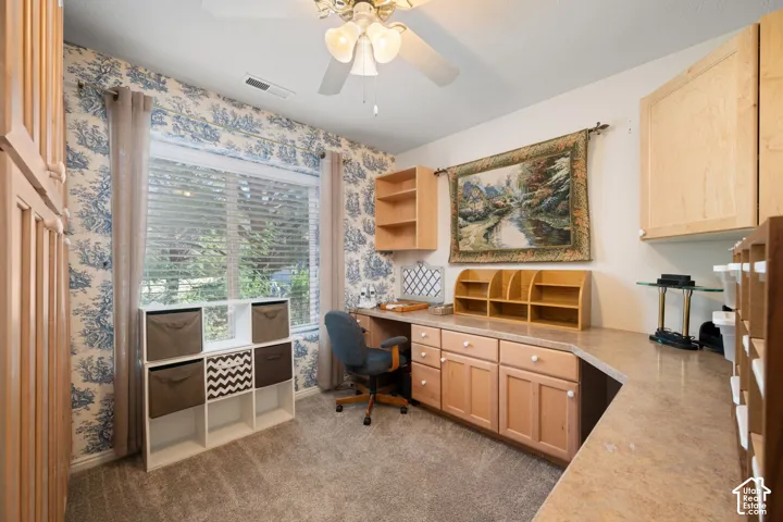 Built-in desk area with wood-finish cabinetry, ample countertop space, and overhead shelving