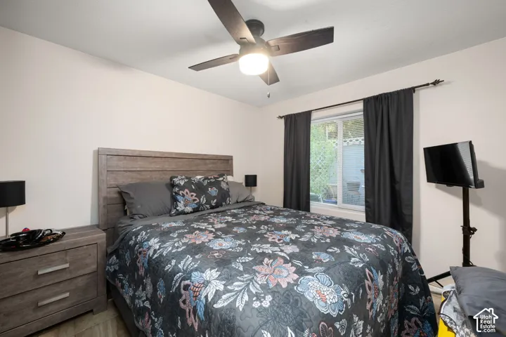 Recessed window with dark drapes, wood-finish flooring, and a ceiling fan with integrated lighting