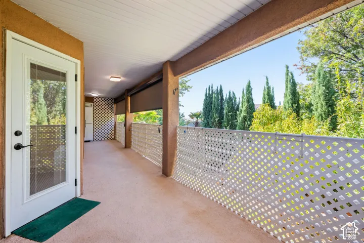Covered outdoor space featuring a white lattice railing and a glass-paneled door