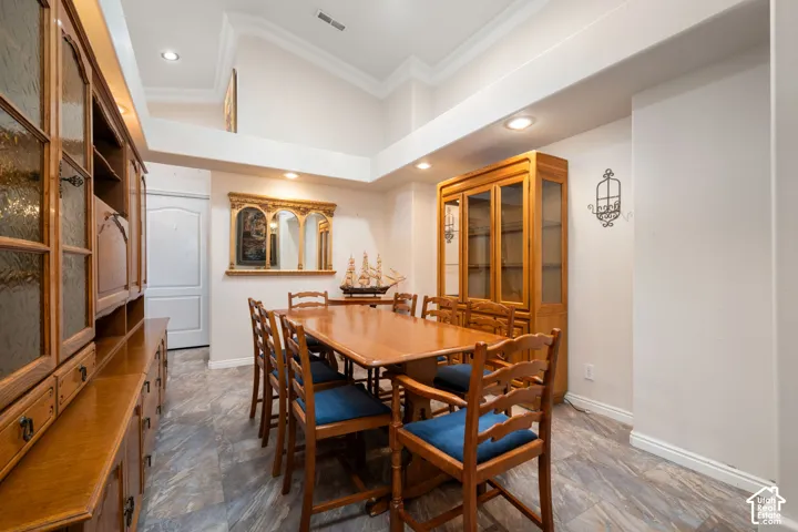 Vaulted ceiling with crown molding, recessed lighting, and wood-finish flooring