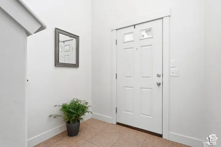White paneled door with upper glass inserts, tile flooring, and crisp white wall finishes