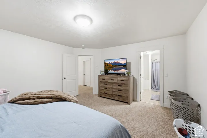 Carpeted room with white walls, a flush-mount ceiling light, and a doorway opening to a bathroom