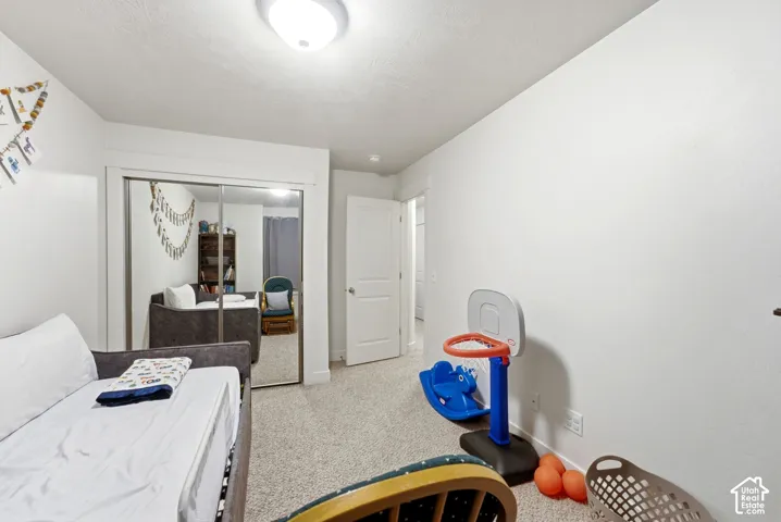 Recessed lighting with a flush-mount fixture, mirrored sliding closet doors, and light-toned carpet flooring
