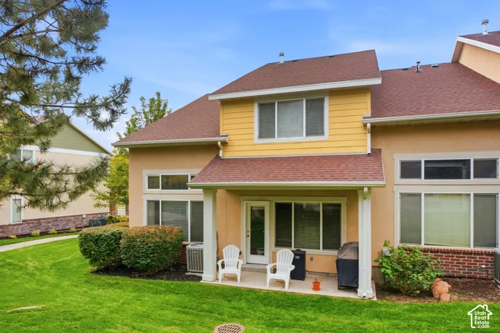 Two-story residence featuring a yellow siding upper level with peaked roofline, complemented by a neutral-toned lower section with brick accents