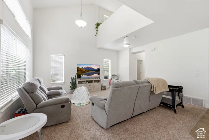 Vaulted ceilings with an upper architectural opening, multiple windows with blinds, and recessed lighting
