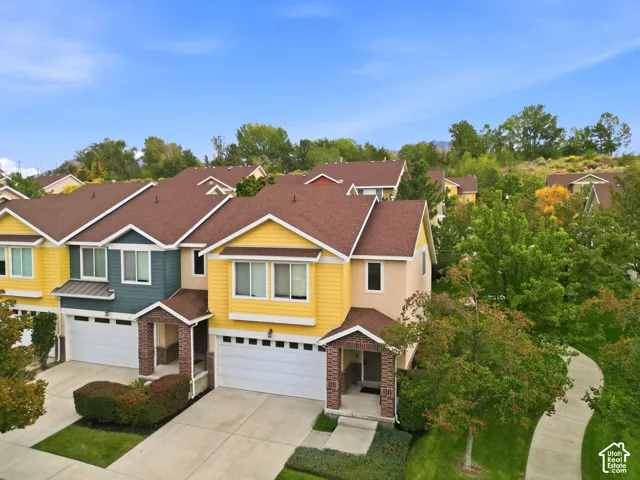 Townhome exterior with varied siding colors, individual garages, covered entryways with brick accents, and a paved walkway