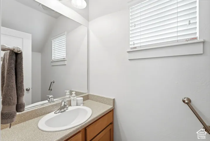 Vanity with integrated oval sink, wood-finish cabinetry, and speckled countertop