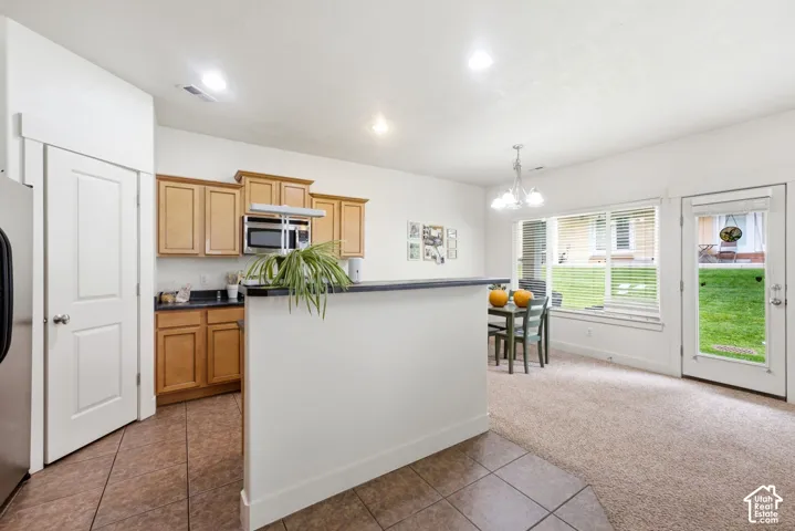 Kitchen with wood cabinetry, dark countertops, and stainless steel microwave