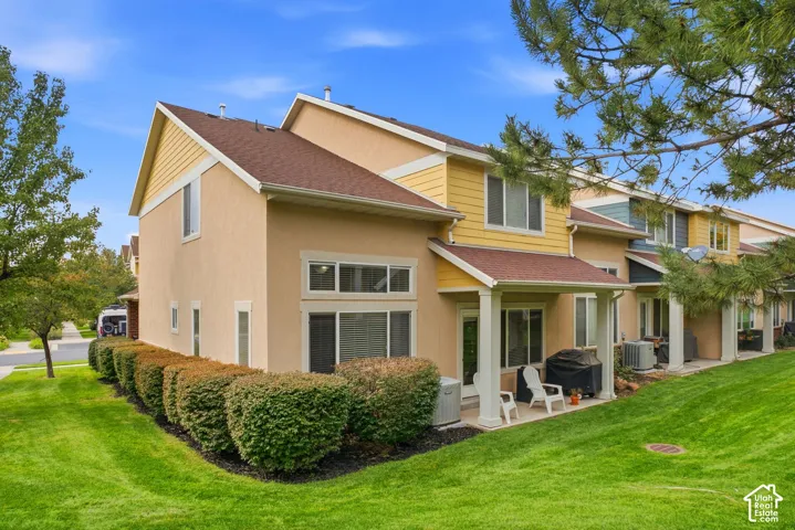 Multi-story residential structure featuring a covered patio, multiple windows, and a sloped lawn