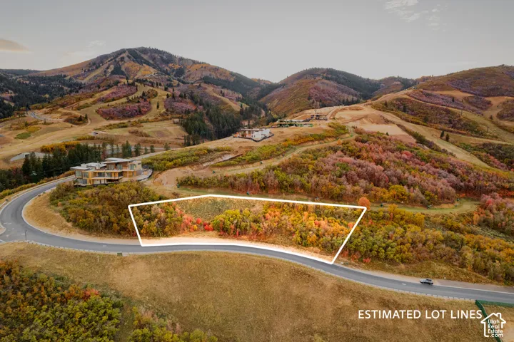 Mountainous terrain with natural vegetation, curved paved road, and distant structures