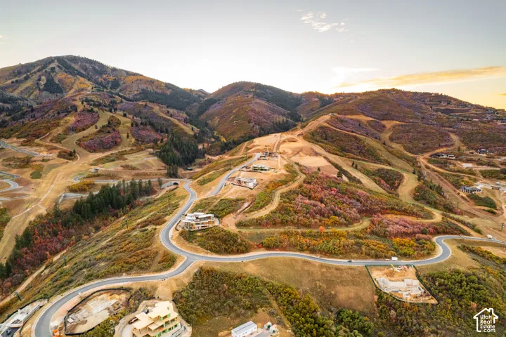 Mountainous terrain with varying elevations, paved roads, scattered residential construction, and diverse tree coverage