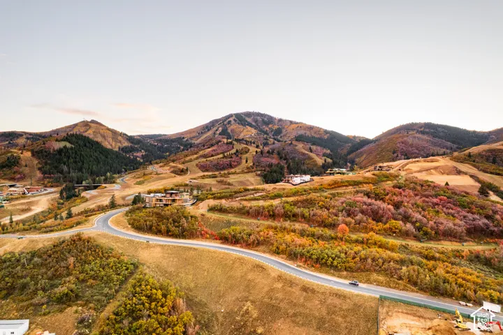 Sweeping mountainous landscape with varied autumn foliage, paved winding roads, and multiple residential structures