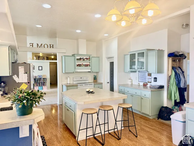 Kitchen featuring an expansive island with seating, wood-finish flooring, recessed lighting, and light blue cabinetry