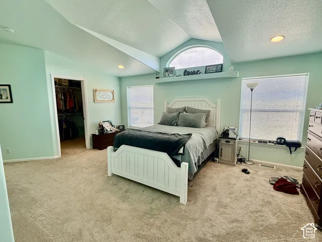 Vaulted ceiling with an arched window, recessed lighting, and a walk-in closet