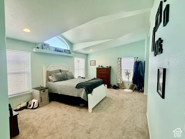 Vaulted ceiling, arched window, recessed lighting, wall-to-wall carpeting, and multiple windows with blinds