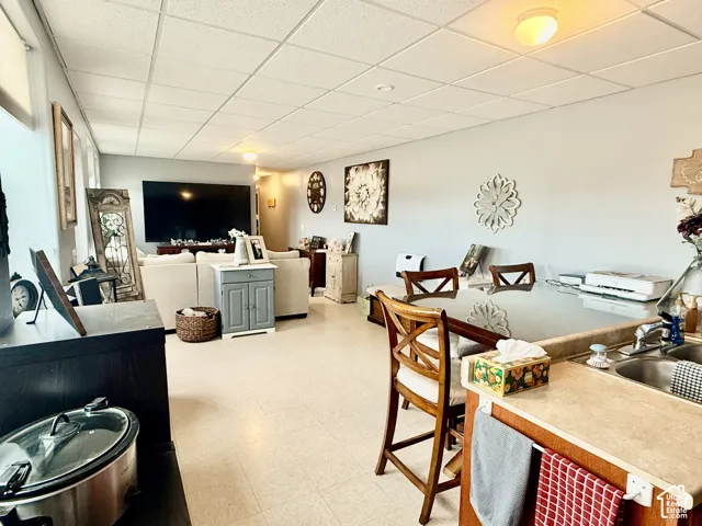Open-concept living space featuring light-toned flooring, recessed lighting, and an integrated counter-height dining area with sink