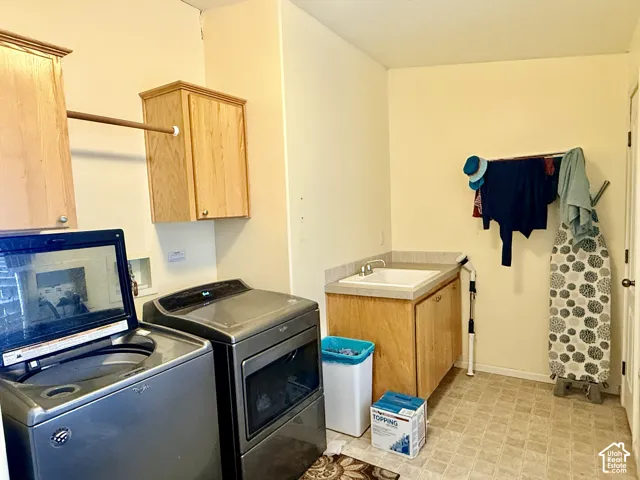 Laundry room featuring built-in cabinetry, a utility sink, a hanging rod, and hard surface flooring