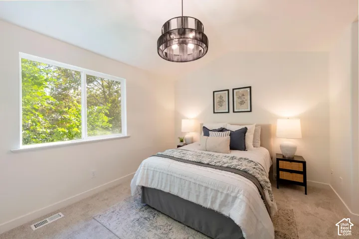Vaulted ceiling, large window, neutral wall paint, carpet flooring, and a modern overhead light fixture