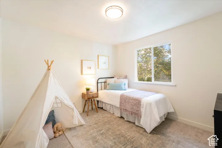 Window featuring outdoor greenery, ceiling-mounted light fixture, light-colored walls, and carpet flooring