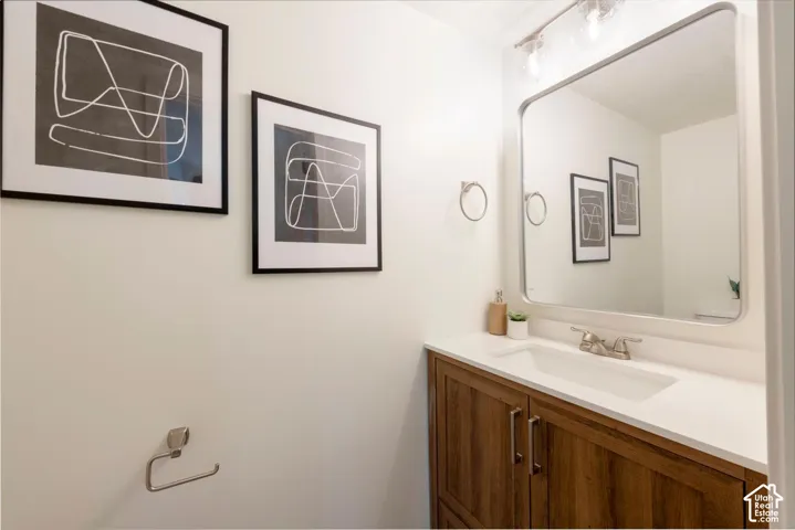 Wood-finish vanity with dual doors, featuring an integrated sink and white countertop