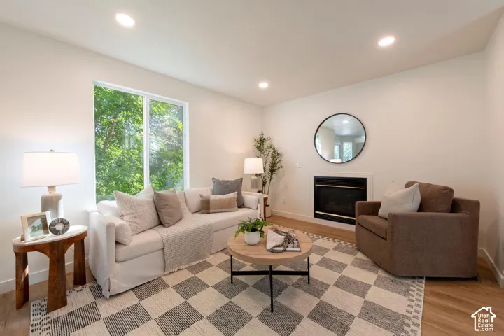 Recessed lighting, large window, fireplace, light wood-finish flooring, and neutral wall paint