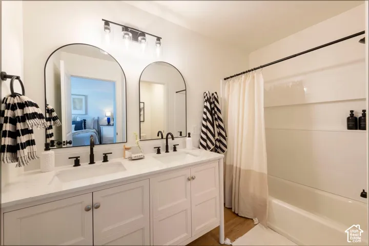 Double vanity with white cabinetry and integrated sinks, matte black fixtures, and arched mirrors
