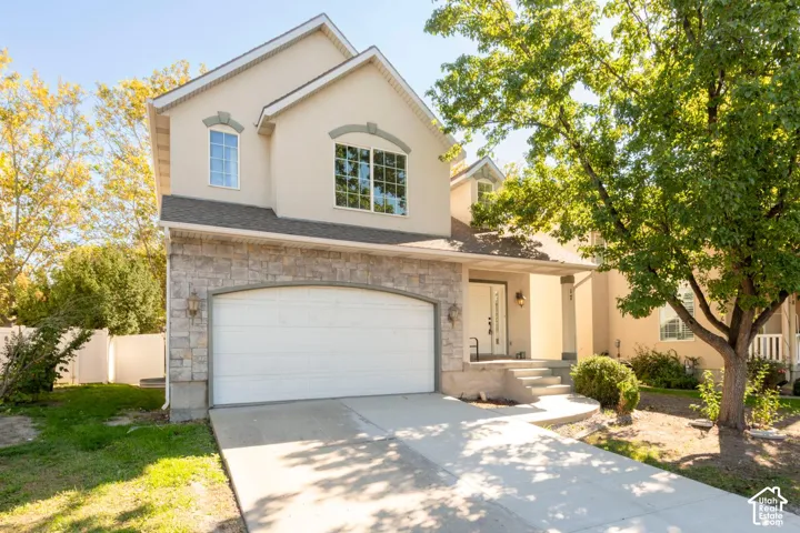 Exterior featuring a stucco facade, stone accents, two-car garage, covered porch, and a concrete driveway