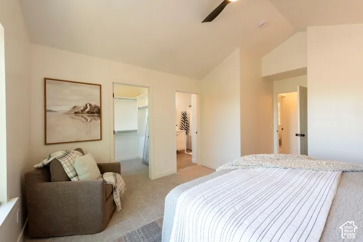 Vaulted ceiling, ceiling fan, neutral wall tones, carpeted flooring, and a walk-in closet
