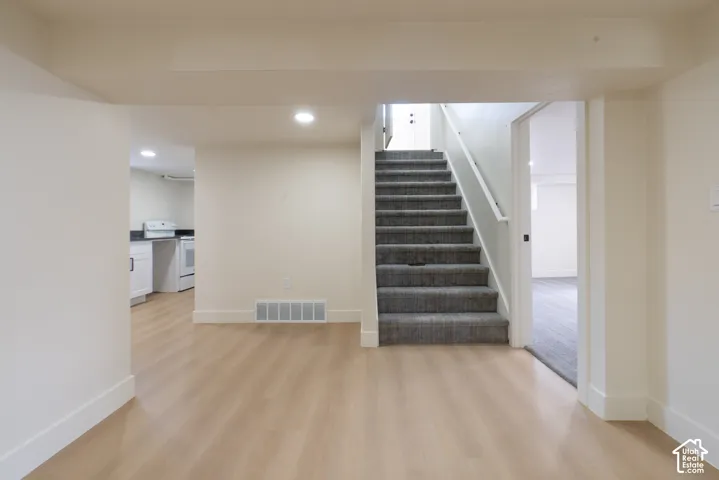 Recessed lighting, wood-finish flooring, white cabinetry, dark countertops, and a carpeted staircase