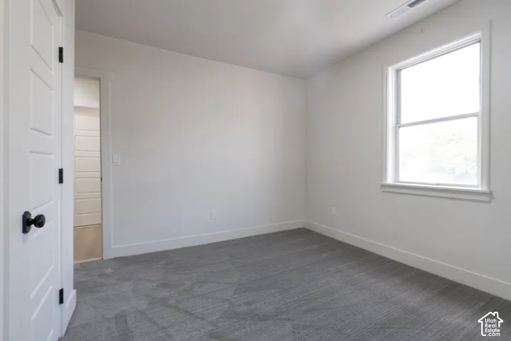 Neutral tone wall finish, gray carpet flooring, white trim, and a white framed window