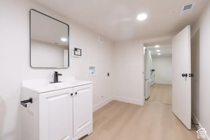 White vanity with a solid surface countertop, matte black faucet, and a rectangular framed mirror