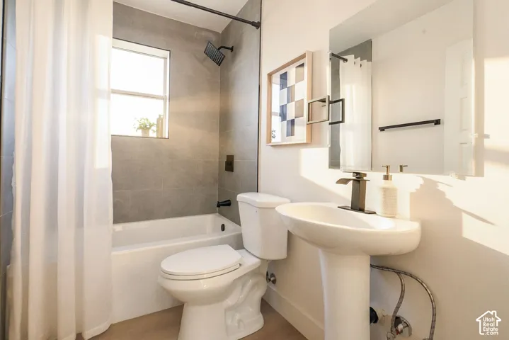 Pedestal sink with black-finish faucet, built-in medicine cabinet, and white tub with tile surround