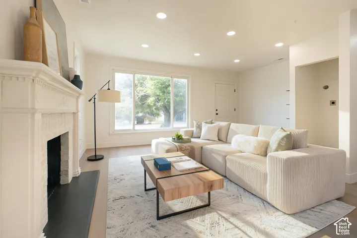 Recessed lighting, wood-finish flooring, white trim, and a decorative fireplace with a mantel