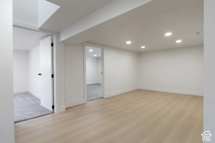 Open living area with light wood-finish flooring, recessed lighting, white walls, and white trim