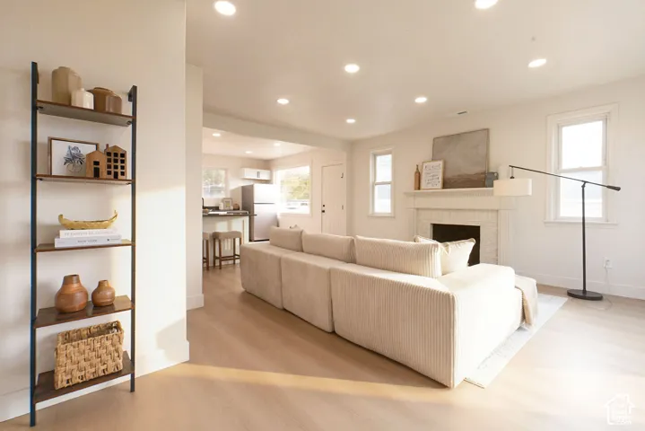 Recessed lighting throughout, wood-finish flooring, white painted walls, white fireplace mantel, and multiple windows