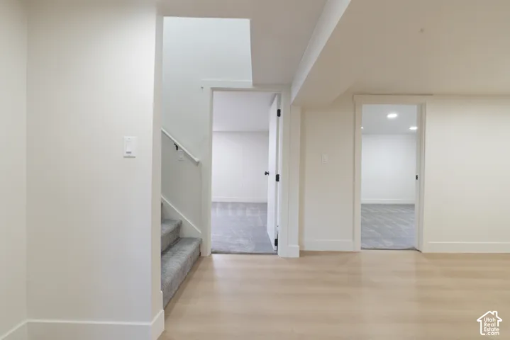 Light wood-finish flooring, white walls, carpeted stairs with white railing, and flush-mount ceiling lighting
