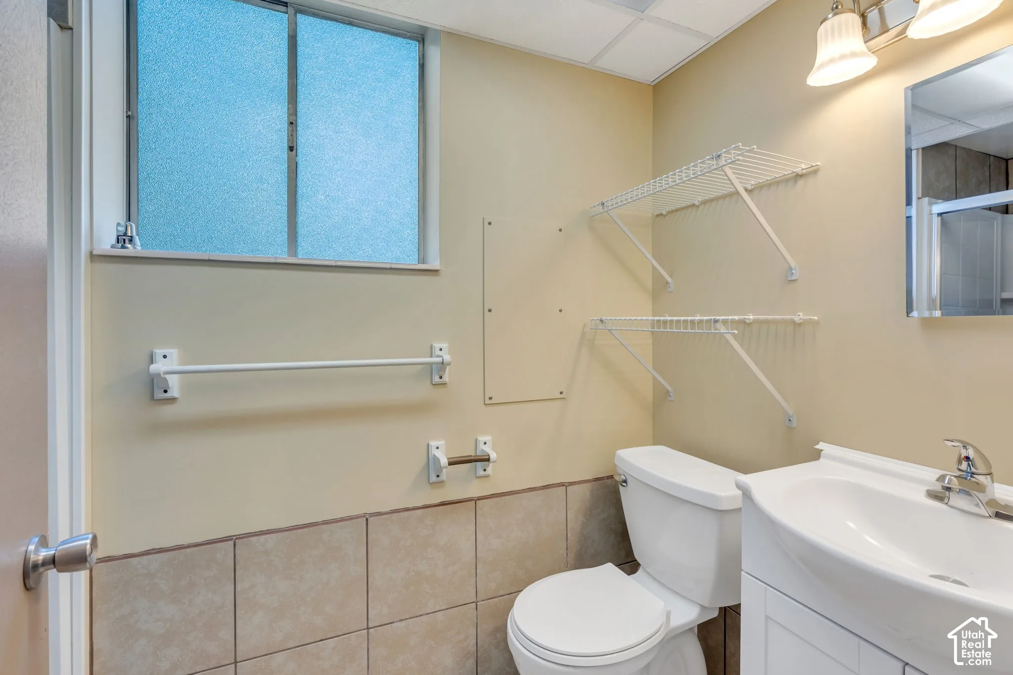 Bathroom with ceramic tile flooring, a white vanity with an integrated sink, and an overhead vanity light fixture