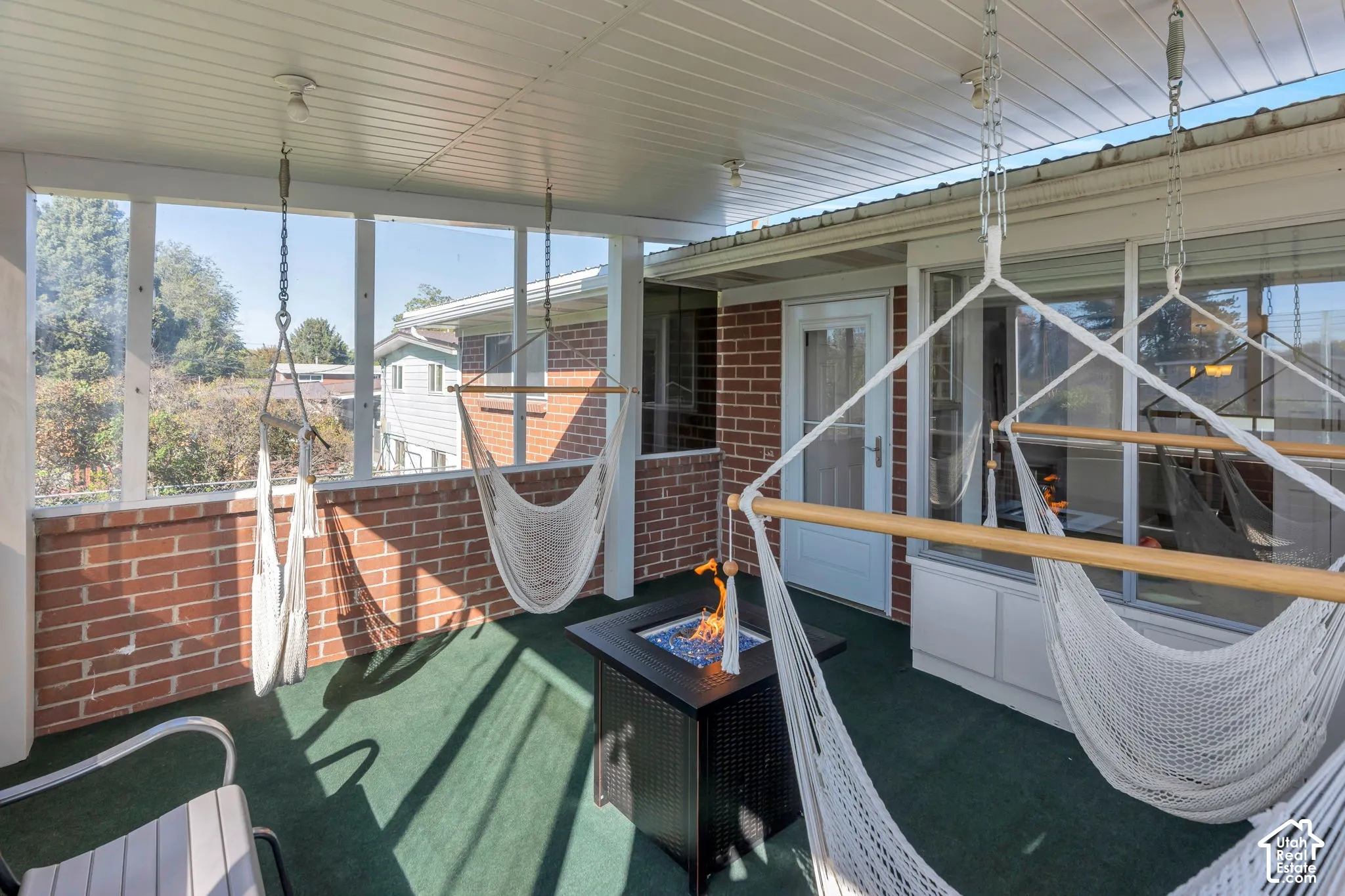 Covered porch featuring a brick half-wall, white window framing, and a white paneled ceiling