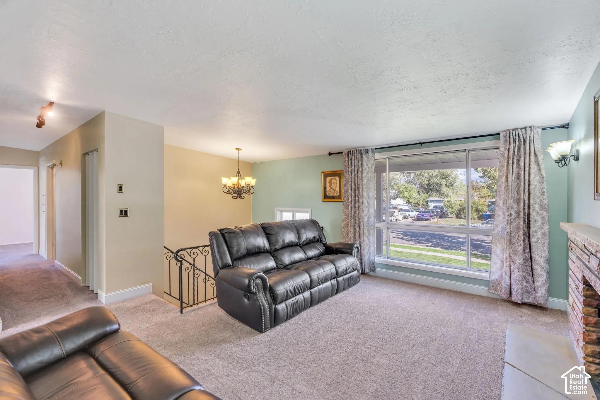 Spacious living area featuring carpet flooring, a large picture window, and a chandelier