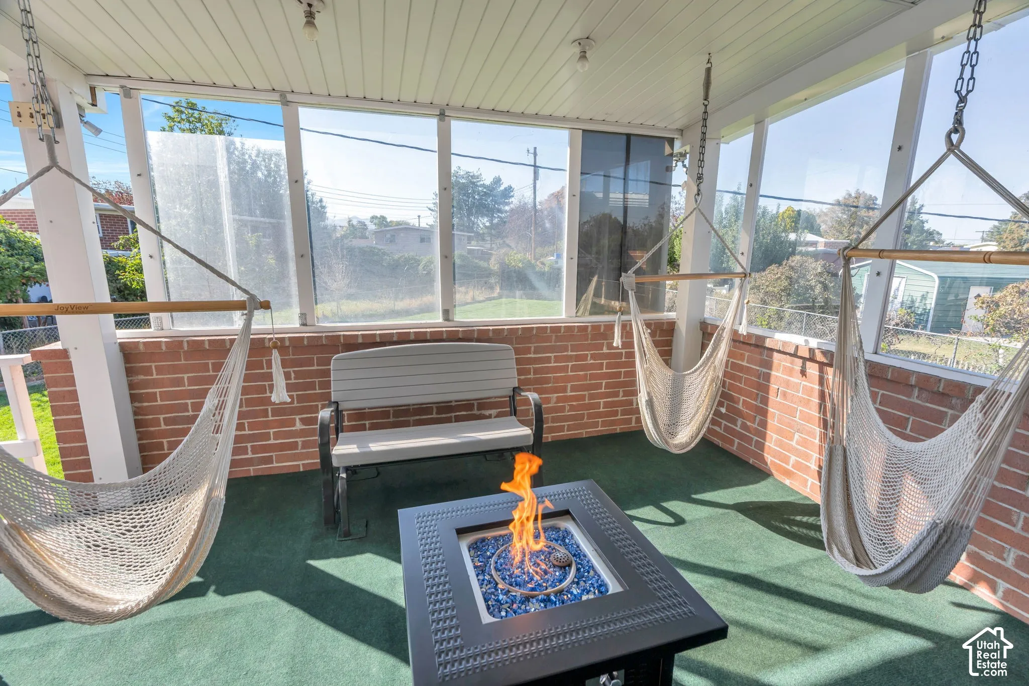 Screened porch featuring brick knee wall, paneled ceiling, and green flooring