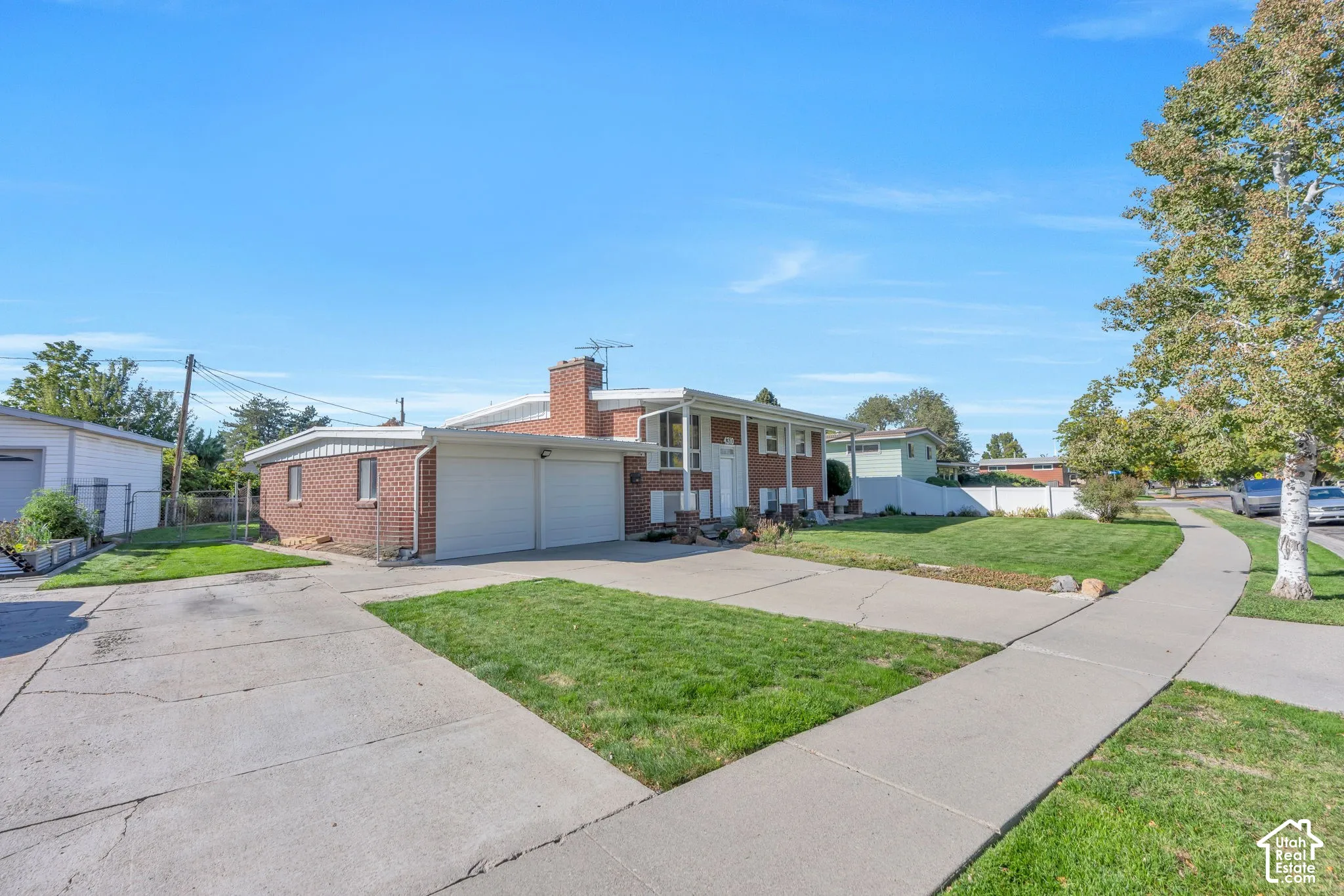 Brick exterior residence featuring a two-car attached garage, expansive concrete driveway, and a separate detached garage structure
