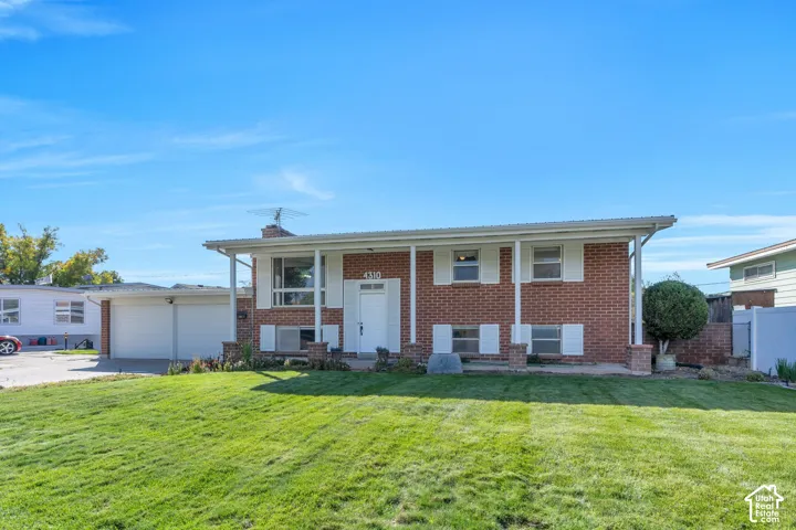 Brick facade with white trim, covered front porch, attached two-car garage, and a lush front lawn