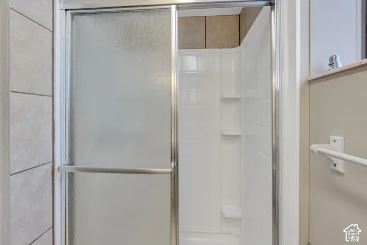 Frosted glass shower enclosure with a stainless steel frame, featuring a white shower surround with integrated shelving