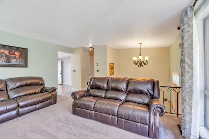 Carpeted living space with a decorative chandelier, a large window, and an ornamental iron railing
