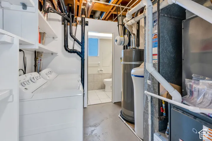 Laundry area featuring built-in shelving, water heater, and water filtration system