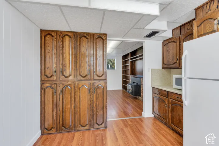 Wood-finish flooring throughout, white paneled walls, extensive wood-finish cabinetry, and solid surface countertops