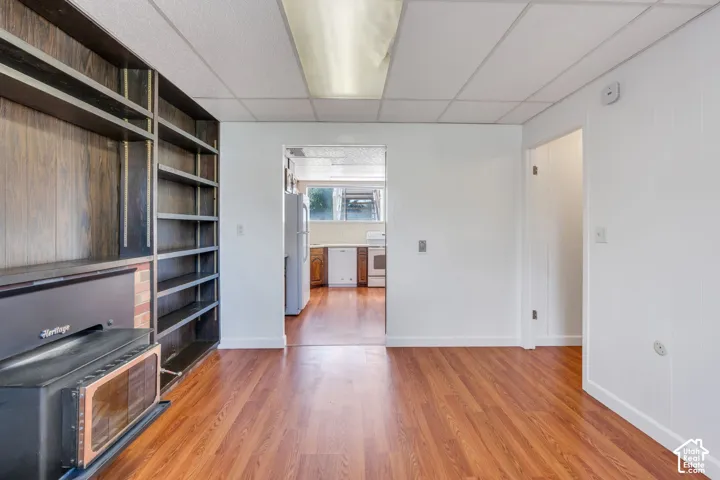 Wood-finish flooring throughout, with a built-in shelving unit featuring a wood panel background and brick detailing