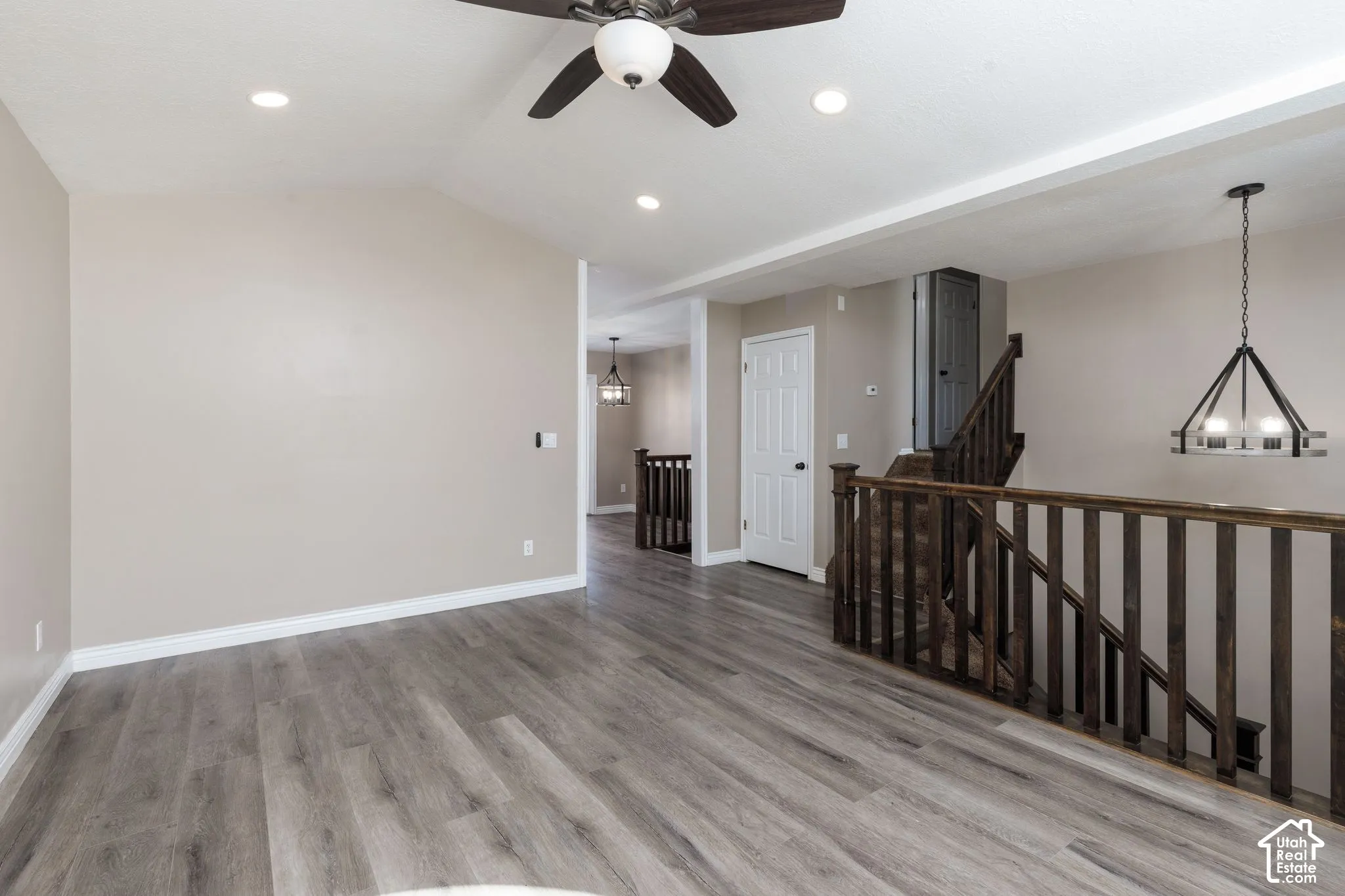 Vaulted ceiling, wood-finish flooring, recessed lighting, ceiling fan, and dark wood baluster railing
